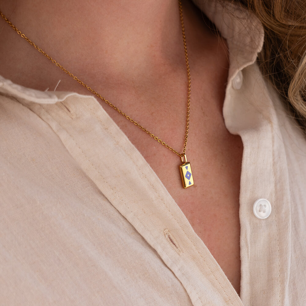 Gold GAIA necklace with a pendant worn by a person in a light-colored shirt.