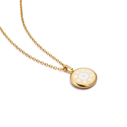 Gold SOLIS necklace with a round pendant featuring a white sun design 