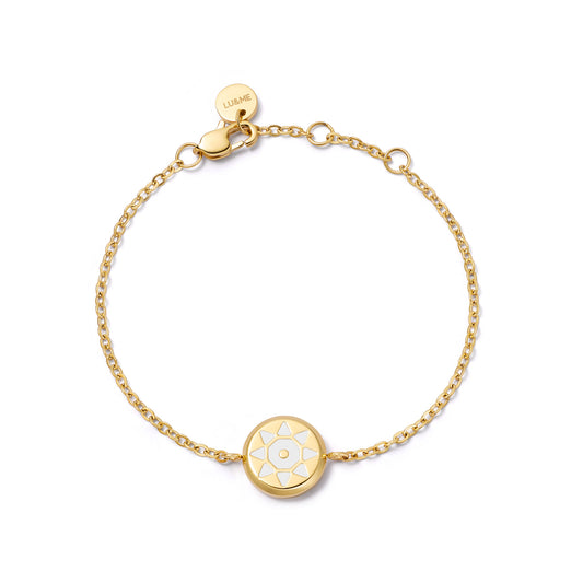 Gold bracelet with a circular charm on a white background