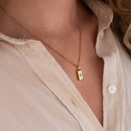 Gold GAIA necklace with a pendant worn by a person in a light-colored shirt.