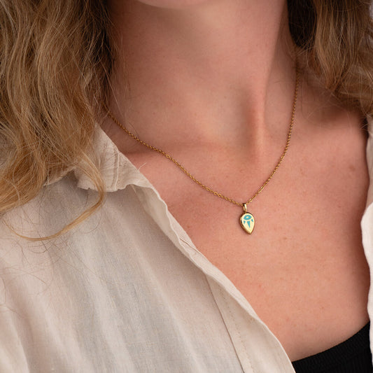 SERENE Necklace with a gold penadant and green design worn by a woman