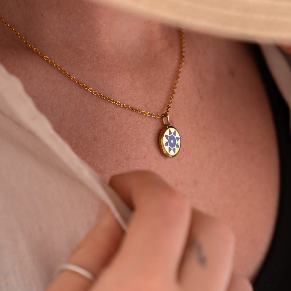 SOLIS Necklace with a small gold pendant with a purple sun worn by a lady