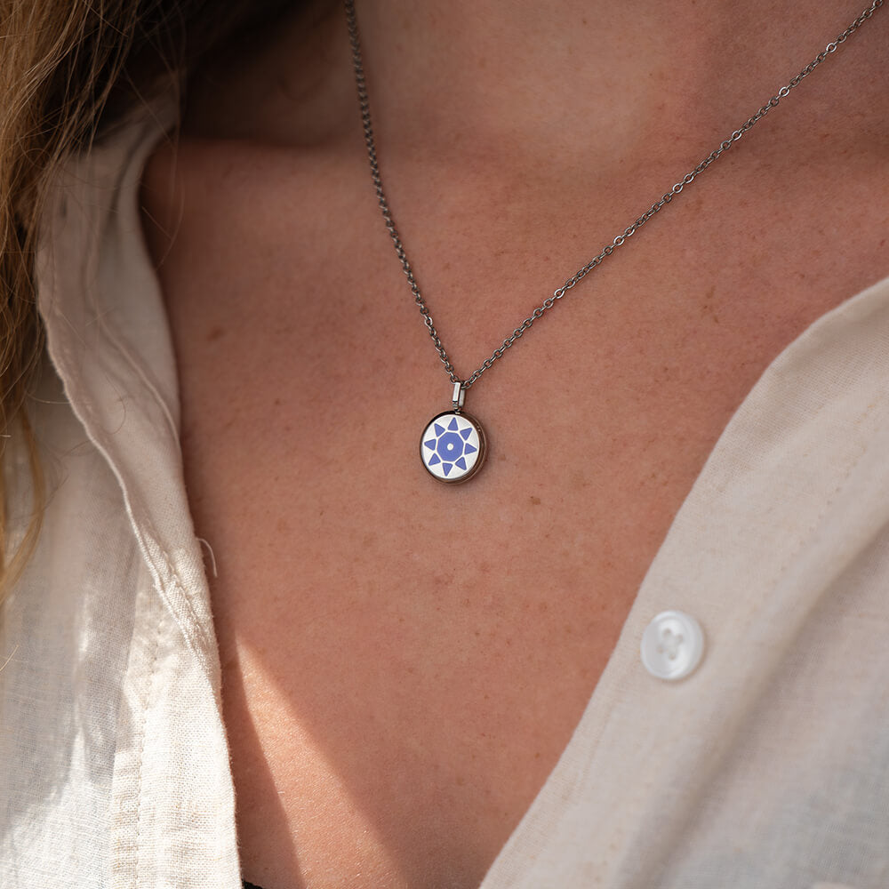 Silver SOLIS necklace with a silver pendant and purple sun detail worn by a person
